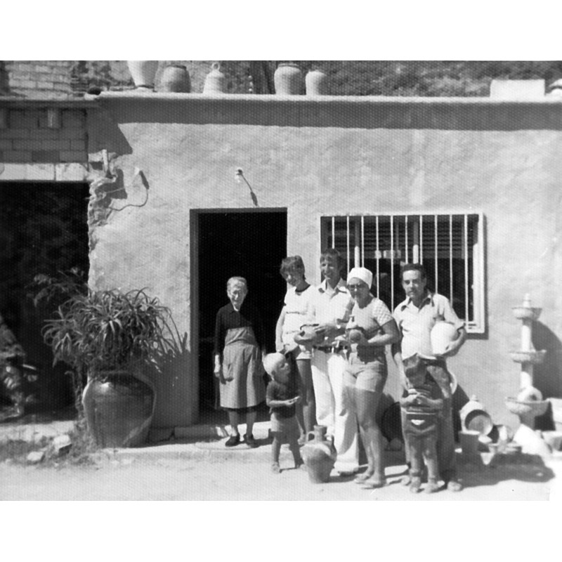 Vicente Prats Marhuenda "el Sord" con su madre y clientes delante de su taller en les teuleres